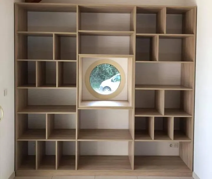 Bibliothèque en chêne à casiers autour d’une fenêtre ronde