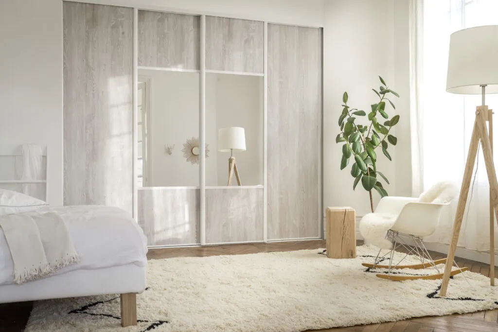 Dressing à portes coulissantes en bois clair et verre dans une chambre